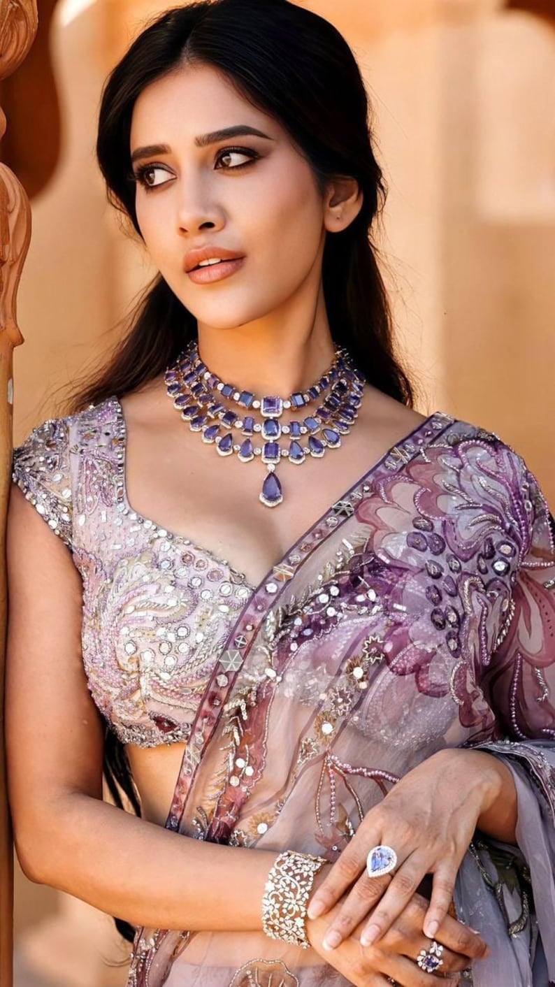 May include: A woman wearing a layered purple gemstone necklace, matching bracelet, and ring. She is wearing a light purple sari with intricate embroidery and a matching blouse. The image is a portrait.