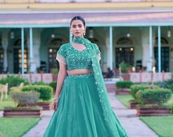 Lehenga Choli em seda verde-água com detalhes em moedas douradas e aplicações de miçangas tubulares.