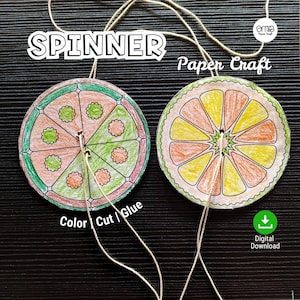 Può includere: Due spinner di carta fatti a mano, ciascuno simile a una fetta di agrume, con segmenti colorati e spago per giocare. Uno è verde e arancione, l'altro giallo e arancione. Il testo recita "SPINNER" e "Paper Craft".