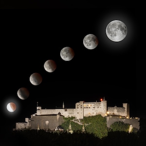 May include: A composite image of a lunar eclipse sequence against a dark night sky. The phases of the moon are displayed in a diagonal line, with a large, illuminated castle at the bottom. The moon's colors range from red to gray.
