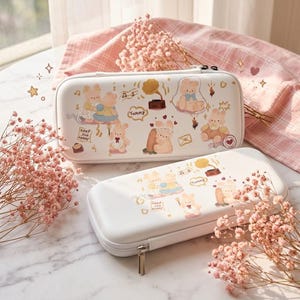 May include: Two white rectangular hard-shell cases with zipper closures, decorated with illustrations of cartoon bears, a gramophone, and the text Yummy and keep you happy. The cases feature a smooth finish and are adorned with small star icons.