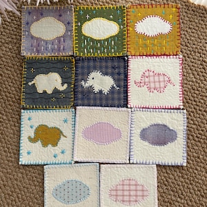 Op de afbeelding: Een verzameling handgemaakte stoffen onderzetters. Sommige hebben olifantenapplicaties, andere hebben wolkvormige patches. De vierkante onderzetters tonen diverse kleuren en patronen en zijn gestikt met contrasterend garen.