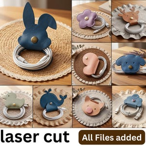 May include: A collection of animal and flower-shaped leather cable organizers featuring snap buttons to secure coiled white charging cords. The set includes designs such as a blue rabbit, purple flower, brown deer, blue dog, green duck, blue whale, pink pig, and blue cloud.