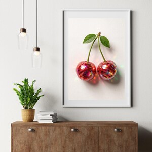 May include: A framed art print featuring two cherries with disco ball-like surfaces. The cherries are red with reflective facets, connected by a green stem and leaves. The artwork is displayed on a white background.
