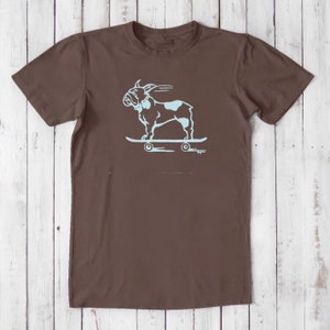 May include: A brown t-shirt with a light blue graphic of a French bulldog skateboarding. The bulldog is wearing a collar and has its tongue sticking out.