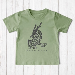 Uni-T kids organic cotton sage green t-shirt featuring a hand-illustrated black dragon graphic and Dare More text.