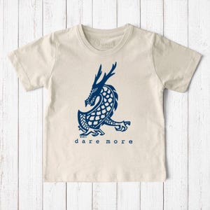 Uni-T organic cotton kids t-shirt in cream with a blue hand-illustrated dragon graphic and Dare More text