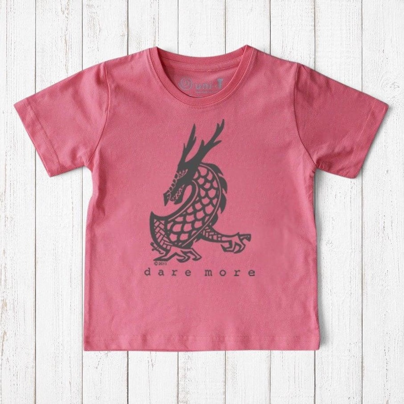 Uni-T kids organic cotton t-shirt in pink featuring a black hand-illustrated dragon graphic with Dare More text