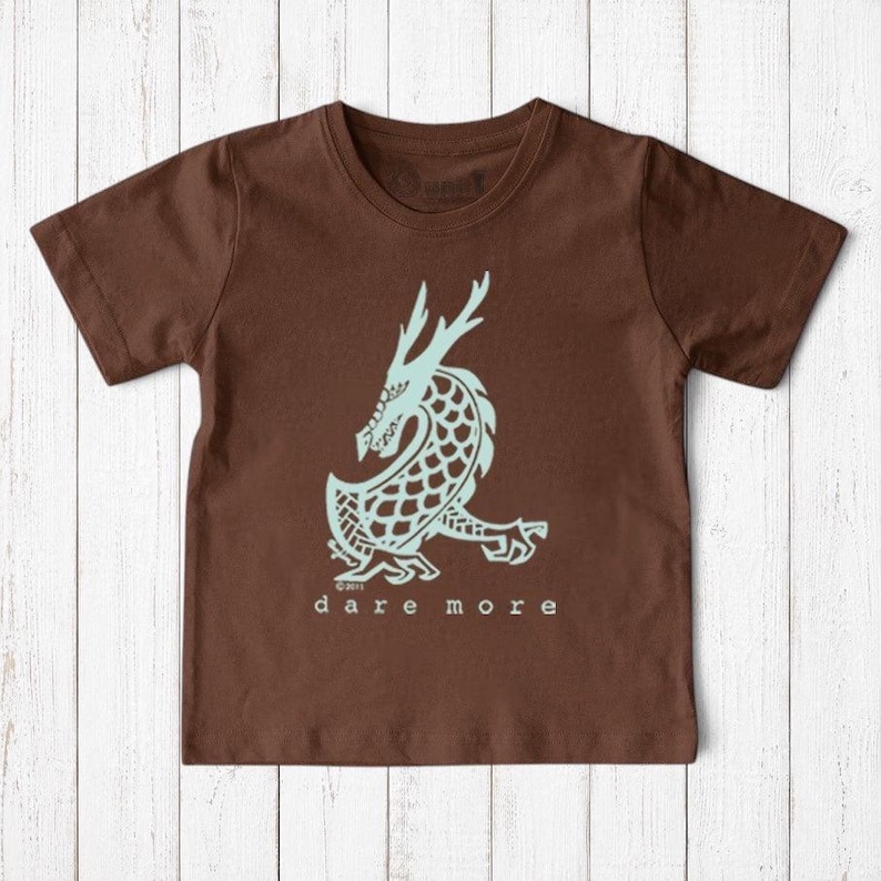 Uni-T kids brown organic cotton t-shirt featuring a light blue hand-illustrated dragon graphic and Dare More text
