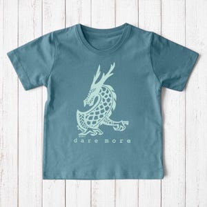 Uni-T kids organic cotton t-shirt in blue featuring a hand-illustrated white dragon graphic and Dare More text