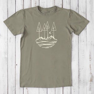 May include: A green t-shirt with a white graphic of a stylized landscape with trees, mountains, and a crescent moon.