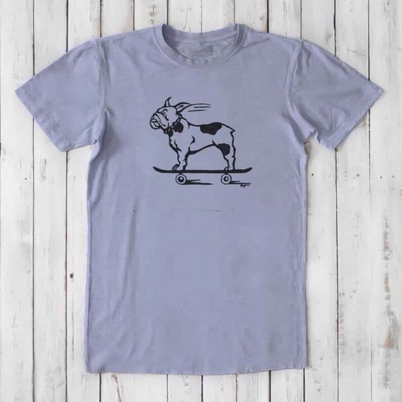 May include: A light blue t-shirt with a black and white illustration of a bulldog skateboarding. The bulldog is wearing a collar and has a tongue sticking out. The skateboard has four wheels.