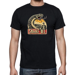 May include: Black t-shirt with a graphic design. The design includes a coiled snake, a bottle with a skull and crossbones, and the words "SNAKE OIL". The graphic uses orange, yellow, and white colours. The t-shirt is worn by a person.