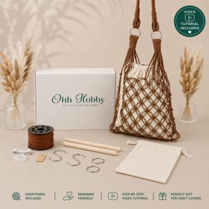 Può includere: Un kit per il fai da te in macramè composto da una scatola bianca con etichetta Ohh Hobby, una bobina di corda marrone, due bastoncini di legno, ganci a S, anelli metallici, un sacchetto color crema e una borsa in macramè marrone con fodera.