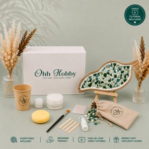 Peut inclure: Un kit de loisirs créatifs comprenant une boîte blanche marquée Ohh Hobby, un plateau mosaïque en forme de feuille, un gobelet en papier, un petit pot, un récipient de poudre, une éponge jaune, un pinceau, quatre bâtonnets en bois et des carreaux verts.