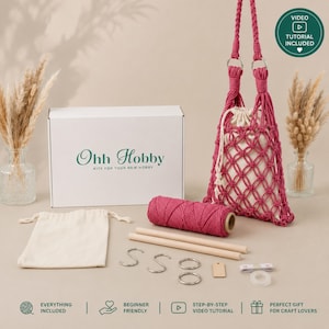 May include: A macrame craft kit featuring a white box labeled Ohh Hobby, a finished magenta knotted bag, a spool of magenta cord, two wooden dowels, metal rings, S-hooks, a small beige drawstring pouch, and a small rectangular wooden tag.