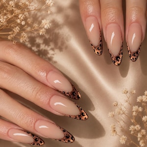 May include: Almond-shaped fingernails featuring a nude base color and a French tip design with a metallic copper and black leopard print pattern. The nails have a glossy finish and are arranged in a display showing the detailed animal print tips.