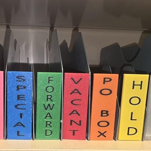 May include: A set of colourful file dividers labelled "TEMP", "SPECIAL", "FORWARD", "VACANT", "PO BOX", and "HOLD". Each divider has a different colour and the text is in black. The dividers are in a metal file organiser.