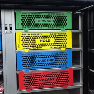 May include: A set of four rectangular metal mail carrier case dividers with a honeycomb pattern. The green divider reads FORWARD, the yellow reads HOLD, the blue reads HARDSHIP, and the red reads VACANT. Each includes the text POSTAL PROPERTY DO NOT REMOVE.