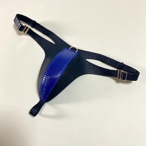 Könnte beinhalten: Ein marineblaues Ledergeschirr mit einem leuchtend blauen Akzent. Das Geschirr verfügt über verstellbare Riemen mit silberfarbenen Metallschnallen und ein strukturiertes blaues Panel. Das Design ist schlank und modern, mit einem Fokus auf kontrastierenden Farben und Texturen.