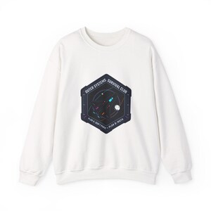Pode incluir: Camisola branca de gola redonda com um gráfico na frente. O gráfico é um hexágono azul escuro com as palavras "Outer Systems Survival Club" e "Plan A: Don't Panic, Plan B: Math". O gráfico apresenta um design com tema espacial.