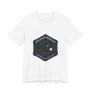 May include: White t-shirt featuring a hexagonal graphic with the text "Outer Systems Survival Club." The graphic includes a spaceship, planet, and the phrases "Plan A: Don't Panic" and "Plan B: Math."