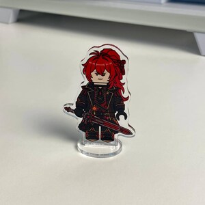 K&ouml;nnte beinhalten: Eine transparente Acrylfigur eines Charakters mit roten Haaren und einem schwarzen Outfit, der ein rotes Schwert h&auml;lt. Die Figur ist im Blockstil gestaltet, &auml;hnlich einem Bausteinspielzeug, und steht auf einem transparenten Sockel.
