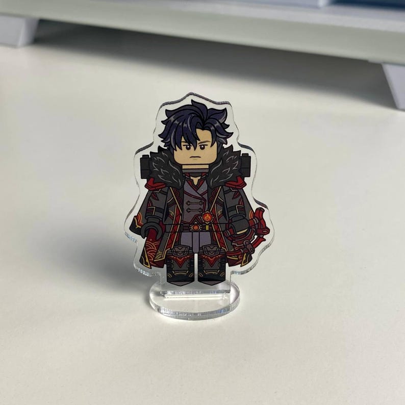 K&ouml;nnte beinhalten: Klare Acrylfigur eines Charakters mit dunklem Haar und ernstem Gesichtsausdruck. Die Figur tr&auml;gt ein detailliertes Outfit mit roten und schwarzen Akzenten und steht auf einem klaren Sockel. Das Design &auml;hnelt einer Miniaturfigur.
