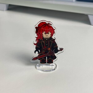 K&ouml;nnte beinhalten: Eine transparente Acrylfigur eines Charakters mit roten Haaren und einem schwarz-roten Outfit, der ein rotes Schwert h&auml;lt. Die Figur ist in einem Blockstil gestaltet und steht auf einem transparenten Sockel.