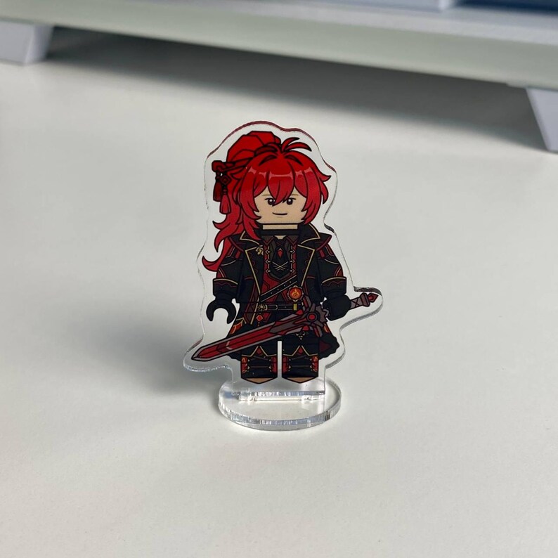 K&ouml;nnte beinhalten: Eine transparente Acrylfigur eines Charakters mit roten Haaren und einem schwarz-roten Outfit, der ein rotes Schwert h&auml;lt. Die Figur ist in einem Blockstil gestaltet und steht auf einem transparenten Sockel.