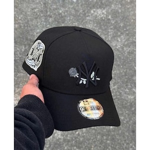 May include: Black 9FORTY adjustable baseball cap with a New York Yankees logo and a rose design. The cap features a Subway Series patch on the side and an adjustable strap.