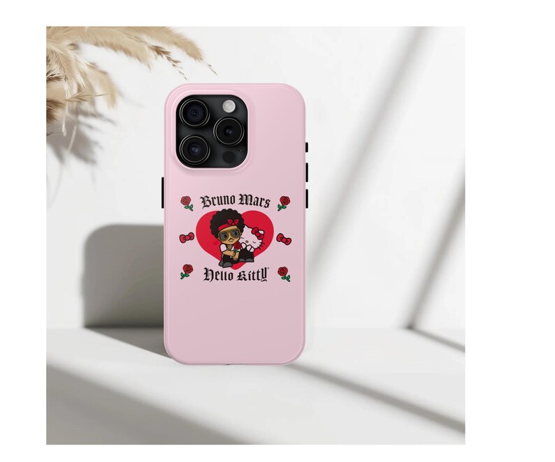 Puede incluir: Funda de tel&eacute;fono rosa claro con un dise&ntilde;o de Bruno Mars y Hello Kitty. El dise&ntilde;o incluye un coraz&oacute;n rojo, rosas y los textos "Bruno Mars" y "Hello Kitty". La funda tiene un recorte para la c&aacute;mara y detalles negros.