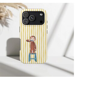 May include: Yellow and white striped phone case featuring a cartoon monkey brushing its teeth while standing on a blue stool. The case has a camera cutout and black side accents.