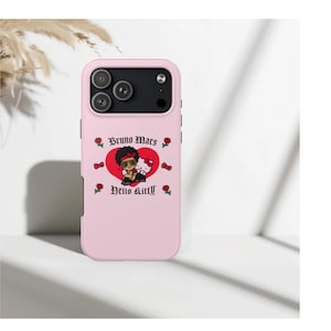 Puede incluir: Funda de tel&eacute;fono rosa con un gr&aacute;fico de dibujos animados de un personaje con gafas de sol, sobre un coraz&oacute;n rojo. El texto "Bruno Mars" y "Hello Kitty" tambi&eacute;n est&aacute; presente, junto con motivos de rosas y corazones.