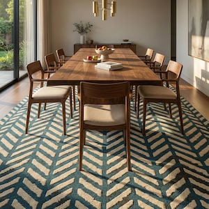 Puede incluir: Un comedor con una mesa larga de madera oscura y ocho sillas de madera con asientos beige. Una alfombra con estampado de chevrón en color turquesa y crema cubre el suelo. Una lámpara de araña de latón cuelga sobre la mesa. La habitación tiene un aparador.