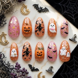 May include: A set of ten almond-shaped press-on nails featuring Halloween themes. The designs include orange and pink glitter bases adorned with 3D pumpkins, white ghosts, black silhouettes of witches on broomsticks, bats, stars, and crescent moons.