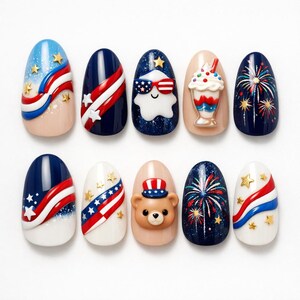 May include: A collection of ten oval-shaped nail designs. The designs feature patriotic themes with red, white, and blue colors, stars, and fireworks. Some nails have 3D bear and ice cream cone embellishments.