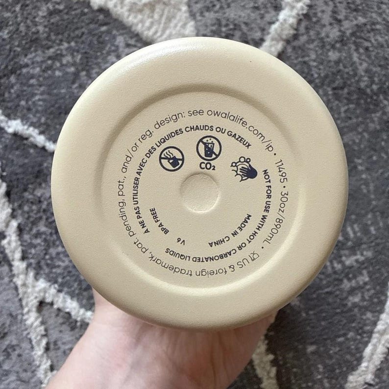 May include: A beige water bottle base with printed text and symbols. The text includes "BPA FREE", "NOT FOR USE WITH HOT OR CARBONATED LIQUIDS", and "30oz/890mL". There are also symbols indicating liquid types and warnings.