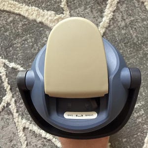 May include: A top-down view of a blue and beige water bottle lid. The lid has a beige flip-top cover and a black handle. The text "Unlock Lock" is printed on a white sticker.