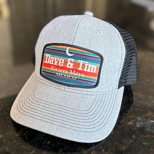 May include: A gray and black trucker hat with a colorful patch that reads "Dave & Tim Riviera Maya MEXICO".