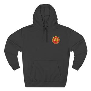 Può includere: Una felpa con cappuccio grigio scuro con tasca a marsupio e coulisse. La felpa presenta un emblema circolare con un disegno di leone dorato su sfondo rosso sul petto superiore sinistro.