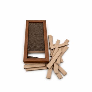 Puede incluir: Un marco rectangular de madera que contiene un inserto de cartón corrugado texturizado de color marrón oscuro, acompañado de un montón de tiras de cartón rectangulares de color marrón claro esparcidas a la derecha y debajo del marco.