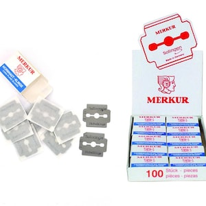 May include: A display box of Merkur razor blades, featuring a red and white logo. The box contains numerous small boxes of blades, each branded with the name. Loose blades and packaging are also visible, with the text "Solingen" and "Hobeikinge".