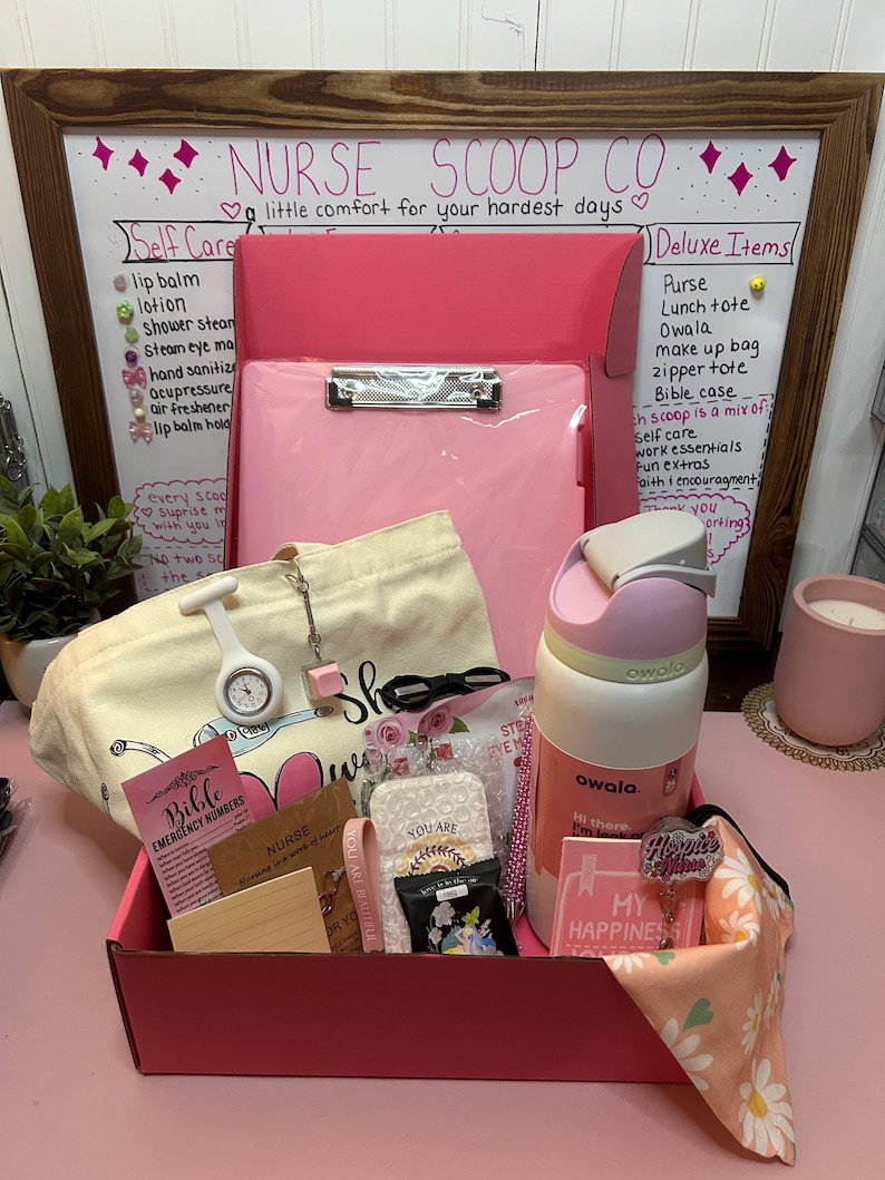 Peut inclure: Une bo&icirc;te cadeau rose contenant un presse-papier rose, un sac fourre-tout en toile cr&egrave;me, une gourde Owala blanche et rose, une montre d'infirmi&egrave;re blanche, un stylo rose, un petit carnet, un tissu &agrave; motifs floraux et diverses petites cartes avec du texte.