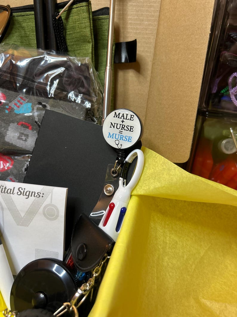 Peut inclure: Un enrouleur de badge rond portant le texte MALE + NURSE = MURSE en lettres noires et bleues avec une ic&ocirc;ne de st&eacute;thoscope. L'enrouleur est fix&eacute; &agrave; un stylo r&eacute;tractable blanc avec des boutons d'encre rouge et bleue, pos&eacute; dans une bo&icirc;te en papier de soie jaune.
