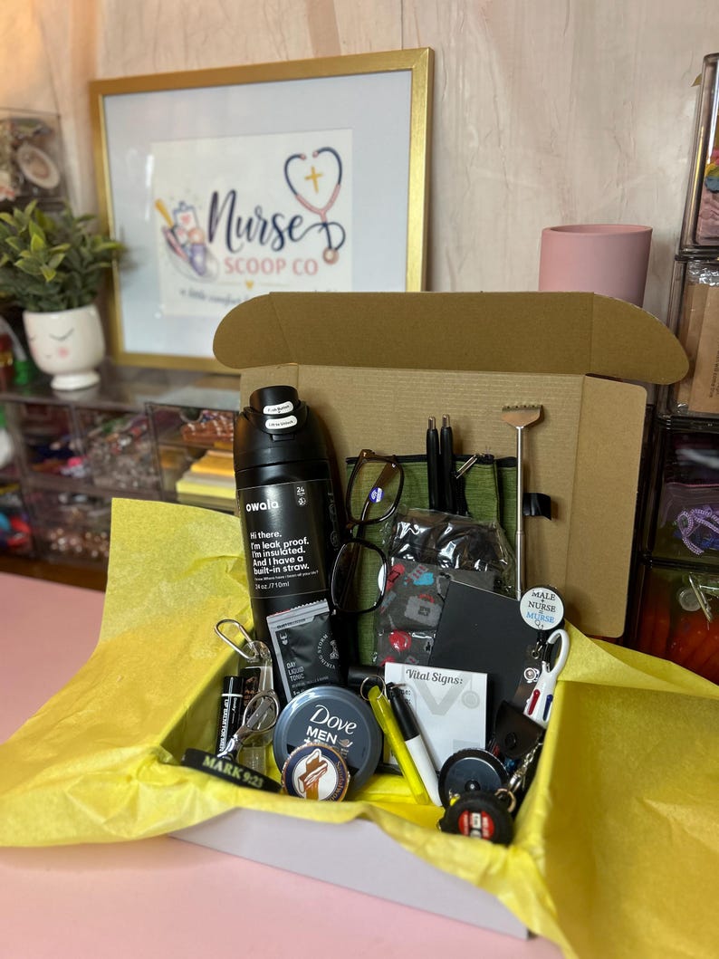 Peut inclure: Une bo&icirc;te cadeau en carton doubl&eacute;e de papier de soie jaune contenant une bouteille d'eau Owala noire de 710 ml, un r&eacute;cipient Dove Men+Care, des lunettes, un carnet noir, un gratte-dos en m&eacute;tal, des stylos, un enrouleur de badge et divers accessoires.