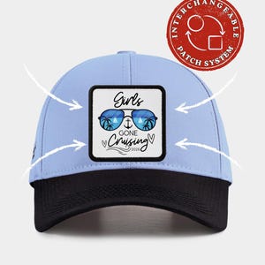 May include: A light blue baseball cap with a black brim and a square patch featuring blue sunglasses, palm trees, an anchor, and the text Girls GONE Cruising 2026. A red circular stamp in the corner reads INTERCHANGEABLE PATCH SYSTEM.