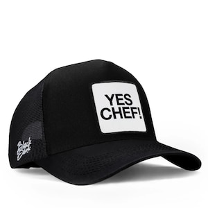 May include: Black trucker hat with a mesh back and a curved brim. The front features a white square patch with the words "YES CHEF!" in bold, black letters. The hat also has a small logo on the side.