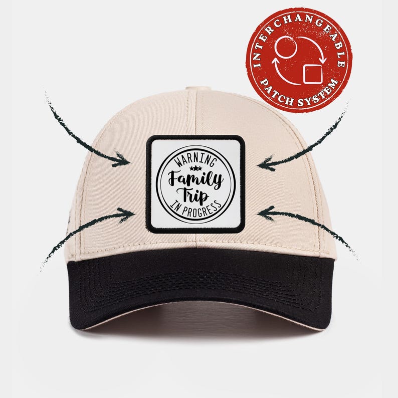 May include: A beige baseball cap with a black brim and a square patch on the front. The patch features a circular design with the text "WARNING Family Trip IN PROGRESS" and three small stars. A red circular icon indicates an interchangeable patch system.