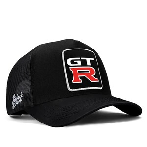 May include: Black baseball cap with a mesh back and curved peak. The front has a white-bordered square patch with "GT" above a red "R". White script text is on the left side.